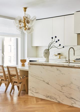 The eat-in kitchen in Carrara marble features a chandelier by Behun and ceramics by Paul S Briggs (left) and Humble Matter (right).