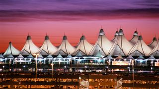 Denver International Airport at dusk with a pink and purple sky.