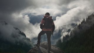 Man gazing down a mountain wearing hiking boots