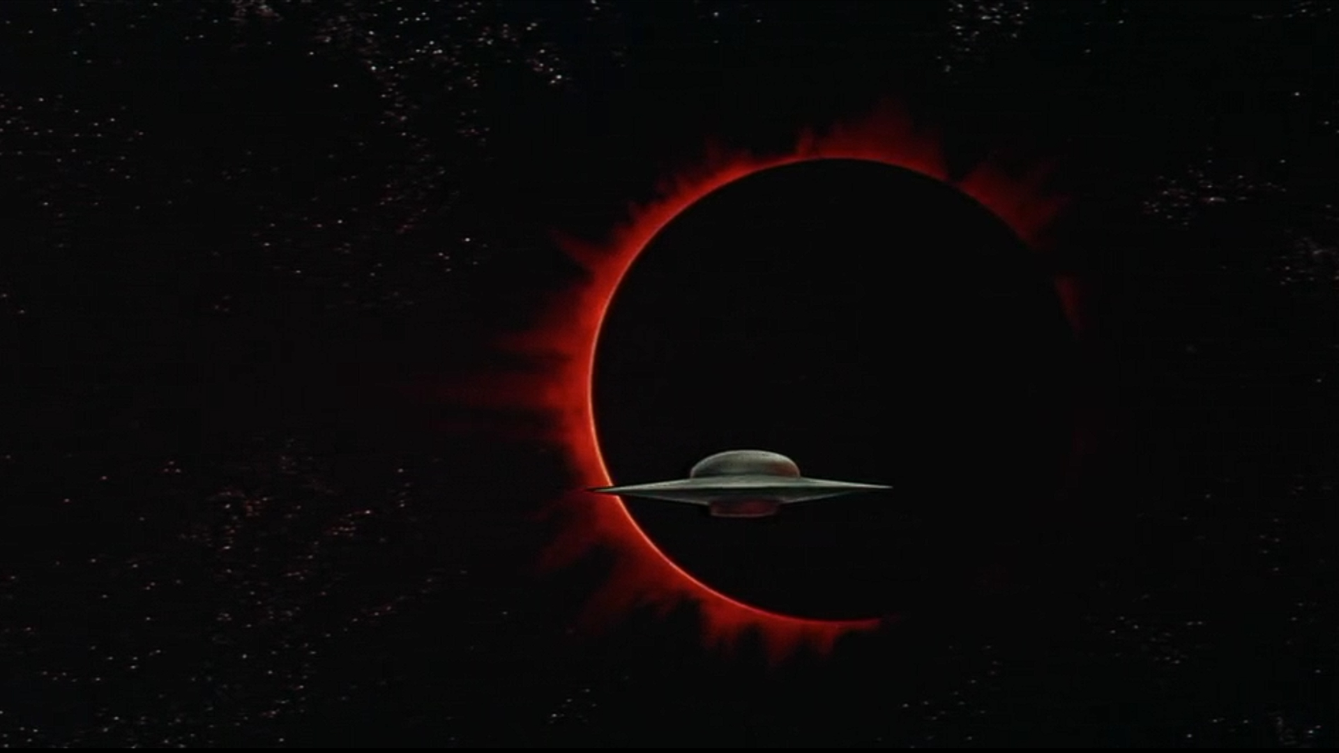Captura de tela do filme de ficção científica de 1956, Forbidden Planet, mostrando um OVNI contra o fundo escuro de um eclipse.