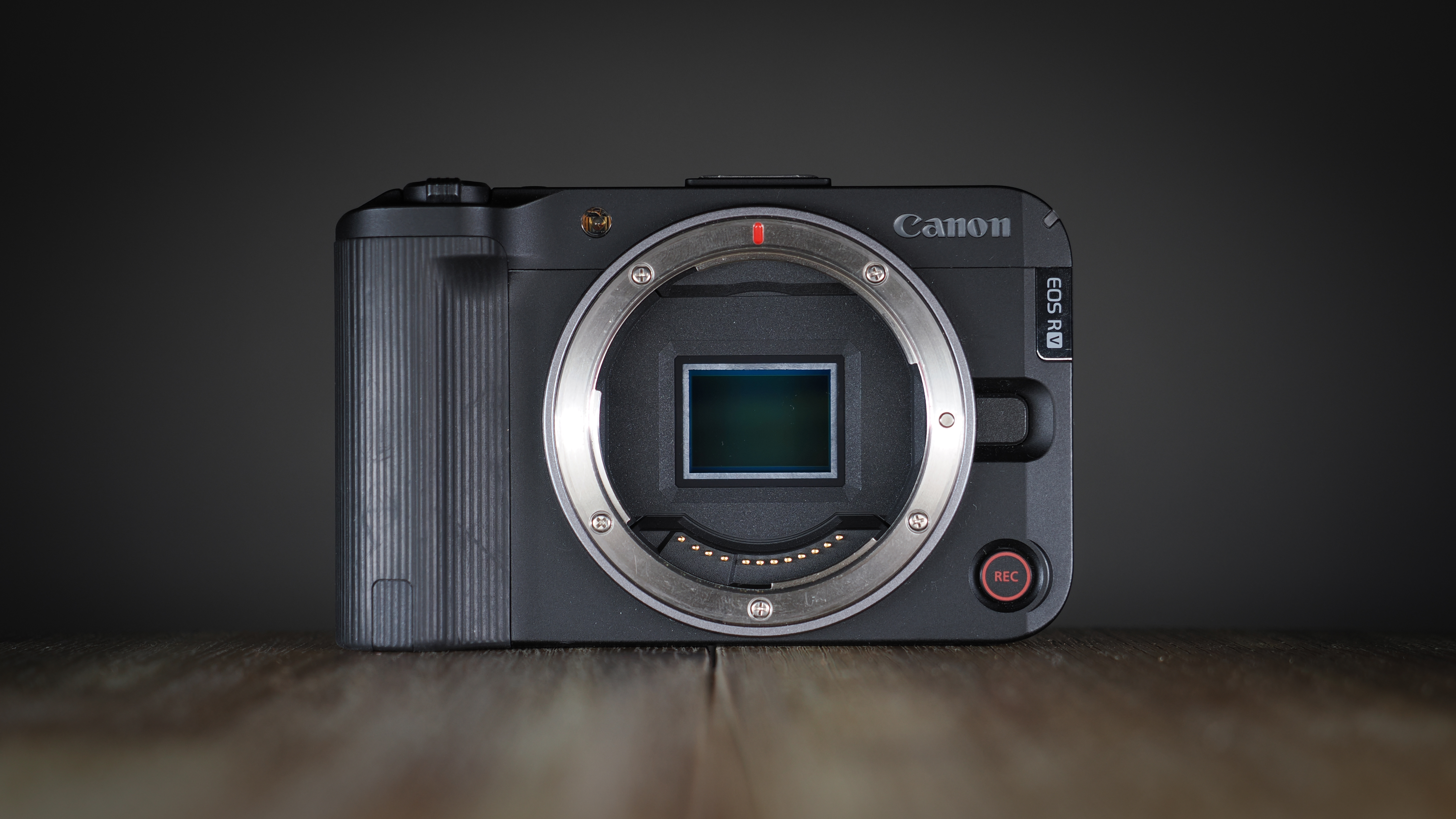Canon EOS R50 V on a wooden surface, against a dark background