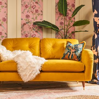 Velvet mustard sofa with accent cushions and feature wallpaper in living room