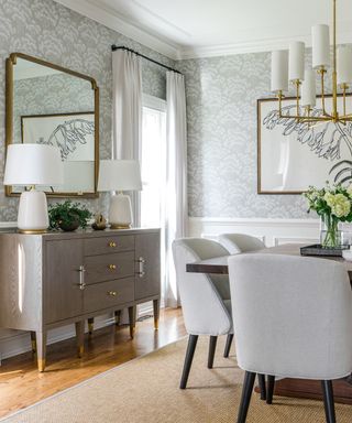 Dining room with wood floor, area rug, gray upholstered dining chairs, table, buffet, mirror and artwork on wall