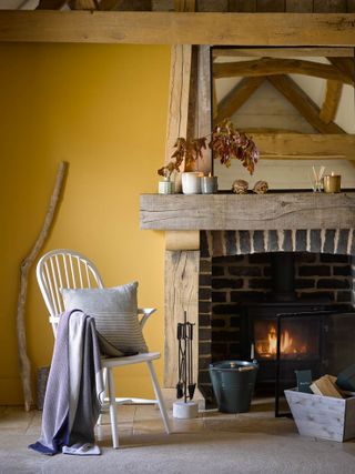 yellow living room with log burner, beams, spindle chair, rustic pieces, farmhouse style, stone floor