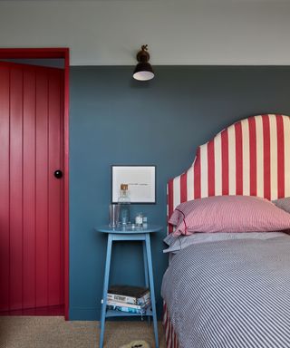 bedroom with blue walls, red and white striped headboard, blue nightstand and red door