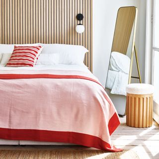 bedroom with wood panelled headboard and red and pink bedspread