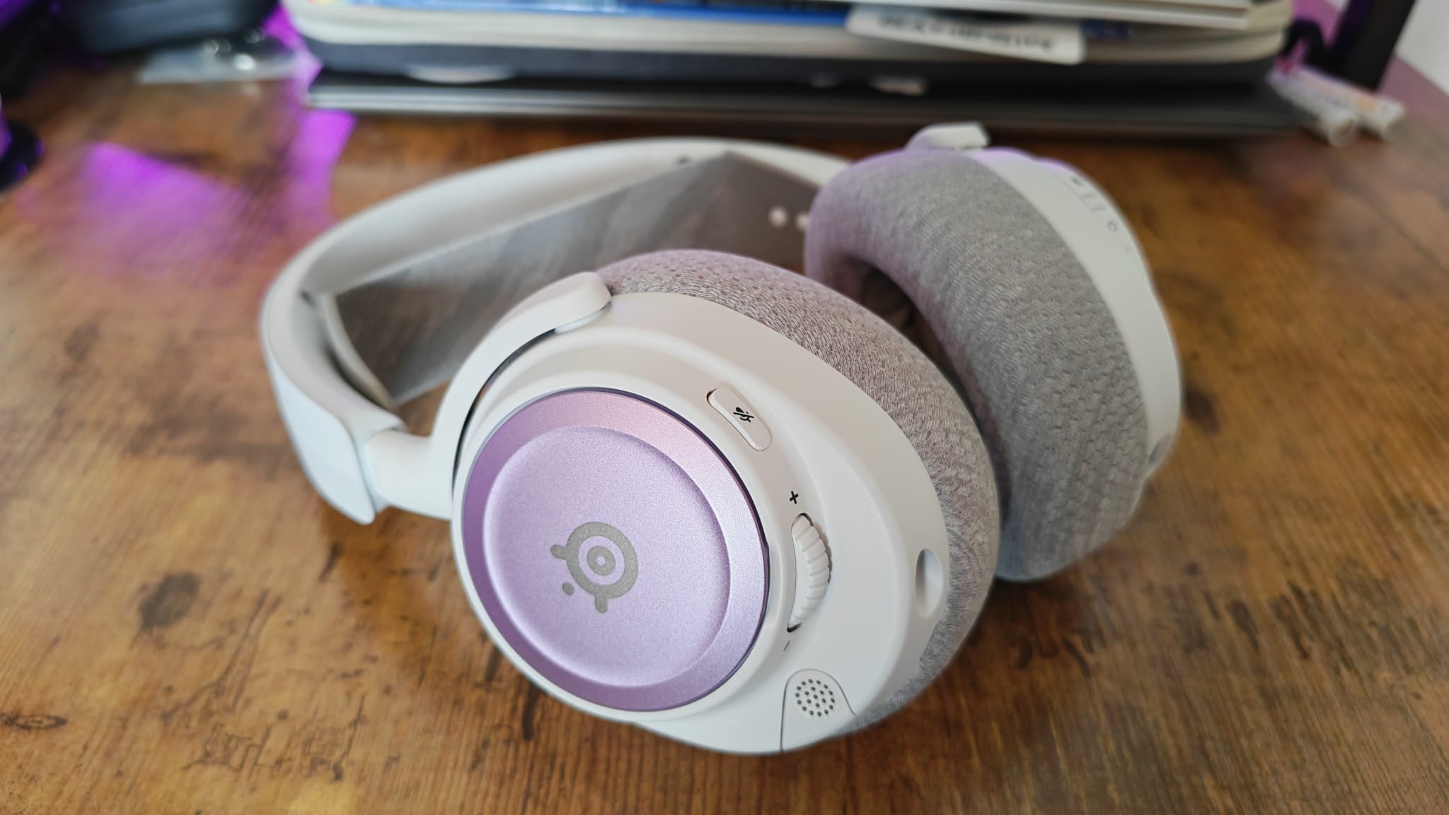 Purple and grey accessories on a white SteelSeries Arctis Nova 7P