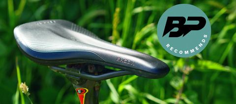 Ergon SR All-Road Core Pro Carbon gravel saddle pictured against grass with a bike perfect recommends badge