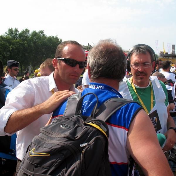 A person from race organizer ASO informs Dirk Nachtergaele that Carlos Barredo will be receiving the combativity prize, so he should head to the podium