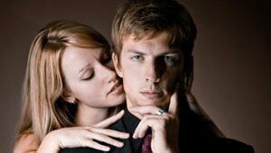 man in suit with woman behind him nuzzling his neck