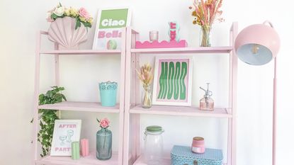 Pink bookshelf dressed with colorful frames and home decor accessories