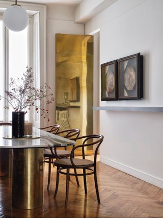 Dining room with gold mirrored wall panel and dining table with gold tubular legs