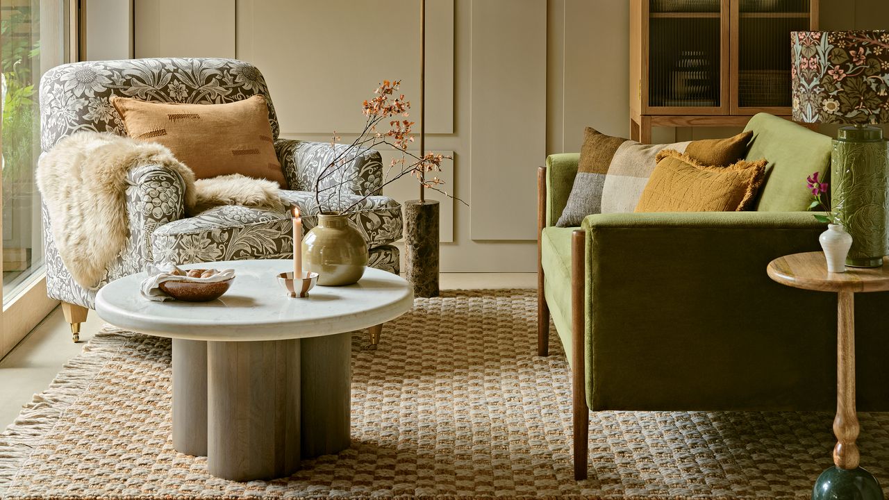 Autumn living room with green velvet sofa, William Morris pattern armchair, natural rug and neutral painted wall 