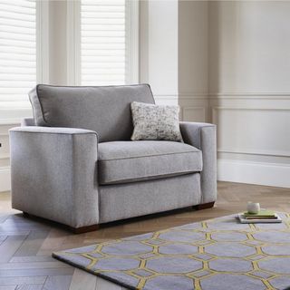 A large chair bed with grey upholstery in a cream living room