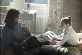 A still from Payback showing Lexie Noble and her daughter sat on a bed