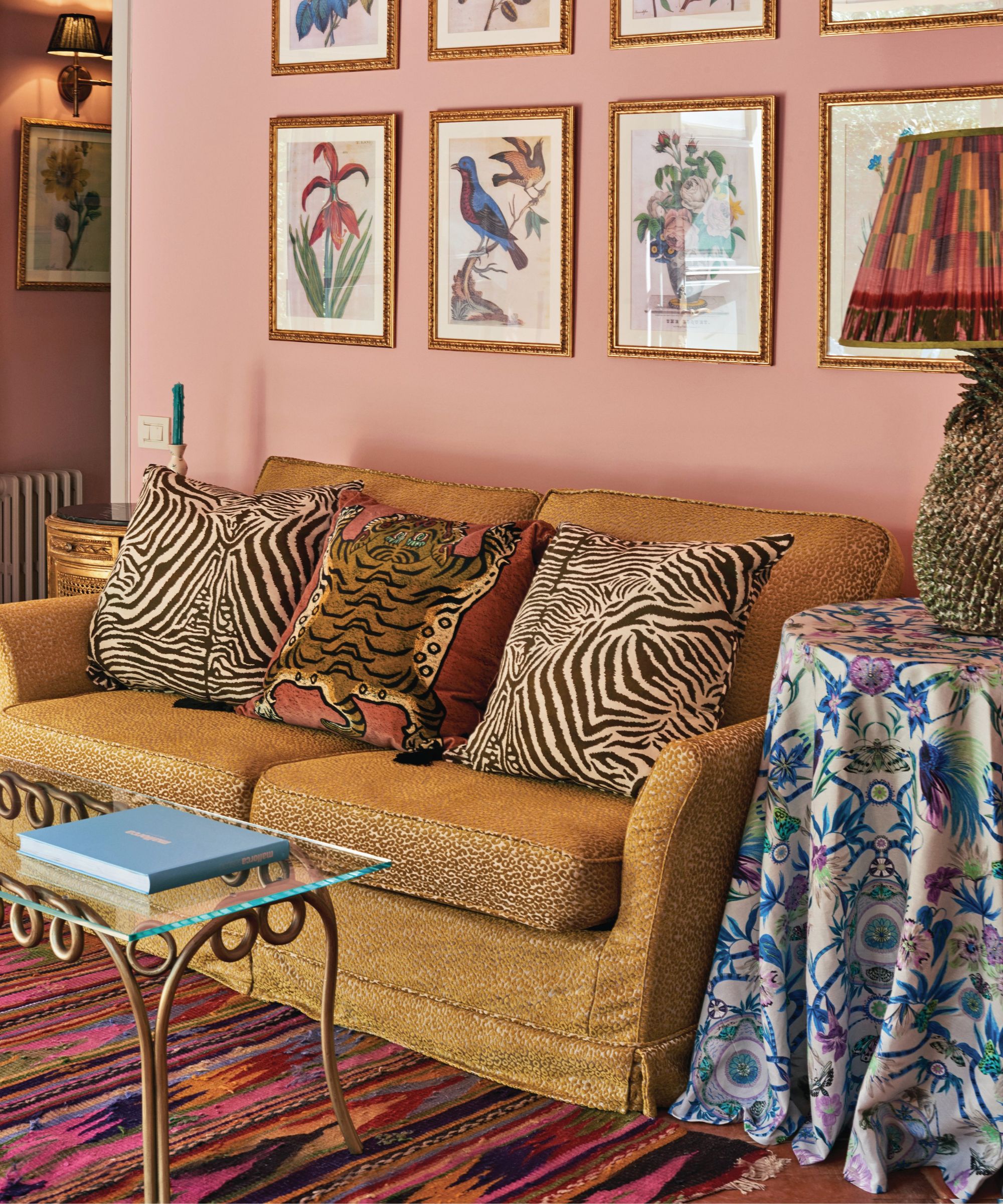 maximal living room with pink wall, gold sofa and gallery wall