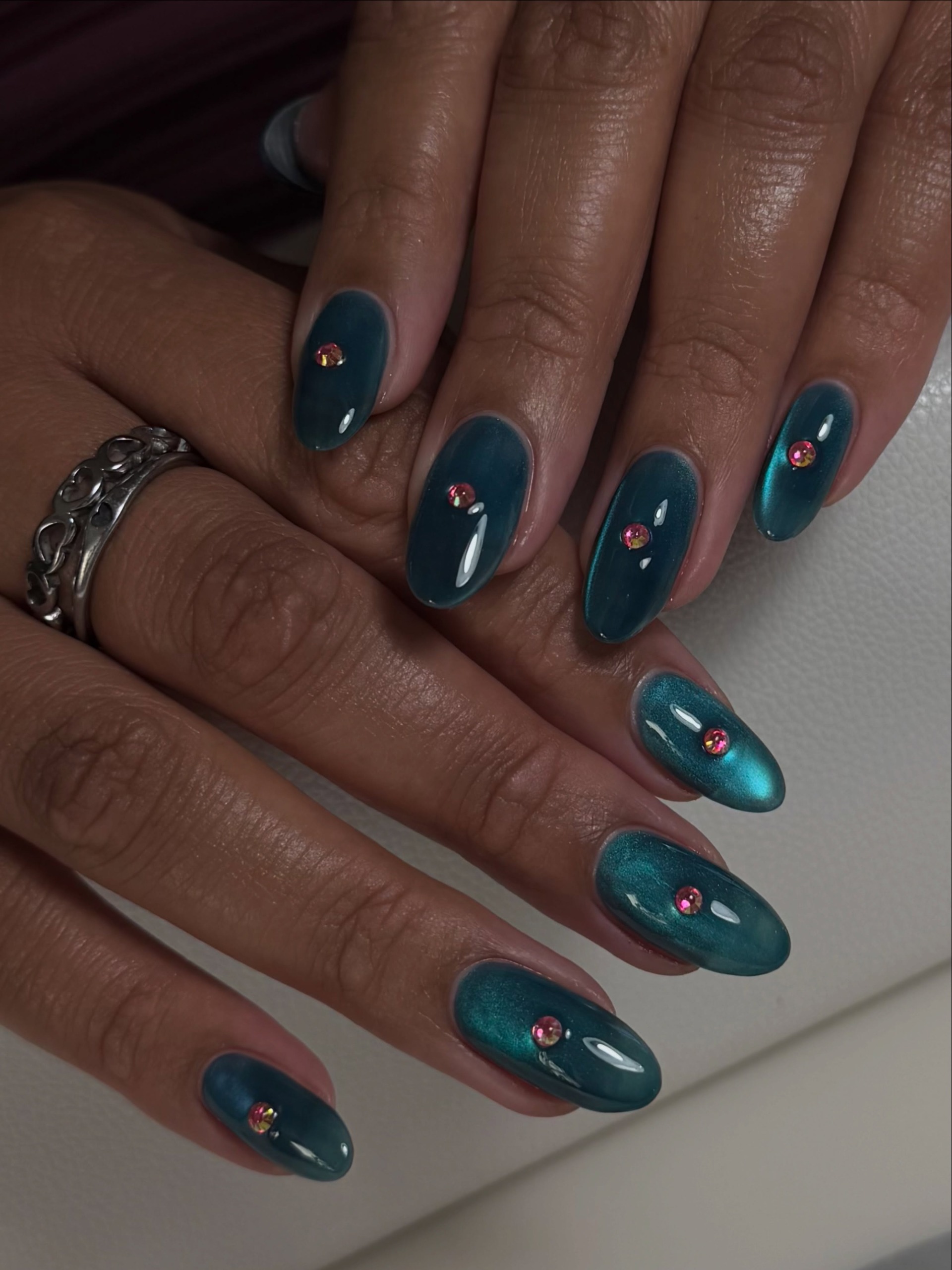 Oval nails in shimmery deep blue with tiny colorful gems scattered across them