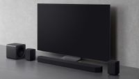 Samsung HW-Q990F soundbar package on a grey backdrop sitting below a TV