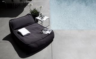 Large black material lounger next to swimming pool