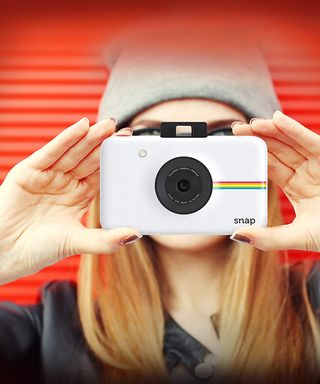 Polaroid Snap white instant camera held in hands of young girl