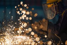 Manual Worker using gas cutting metal in a workshop.