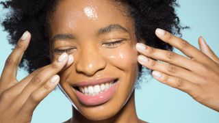 Young female applying glossy make-up - stock photo