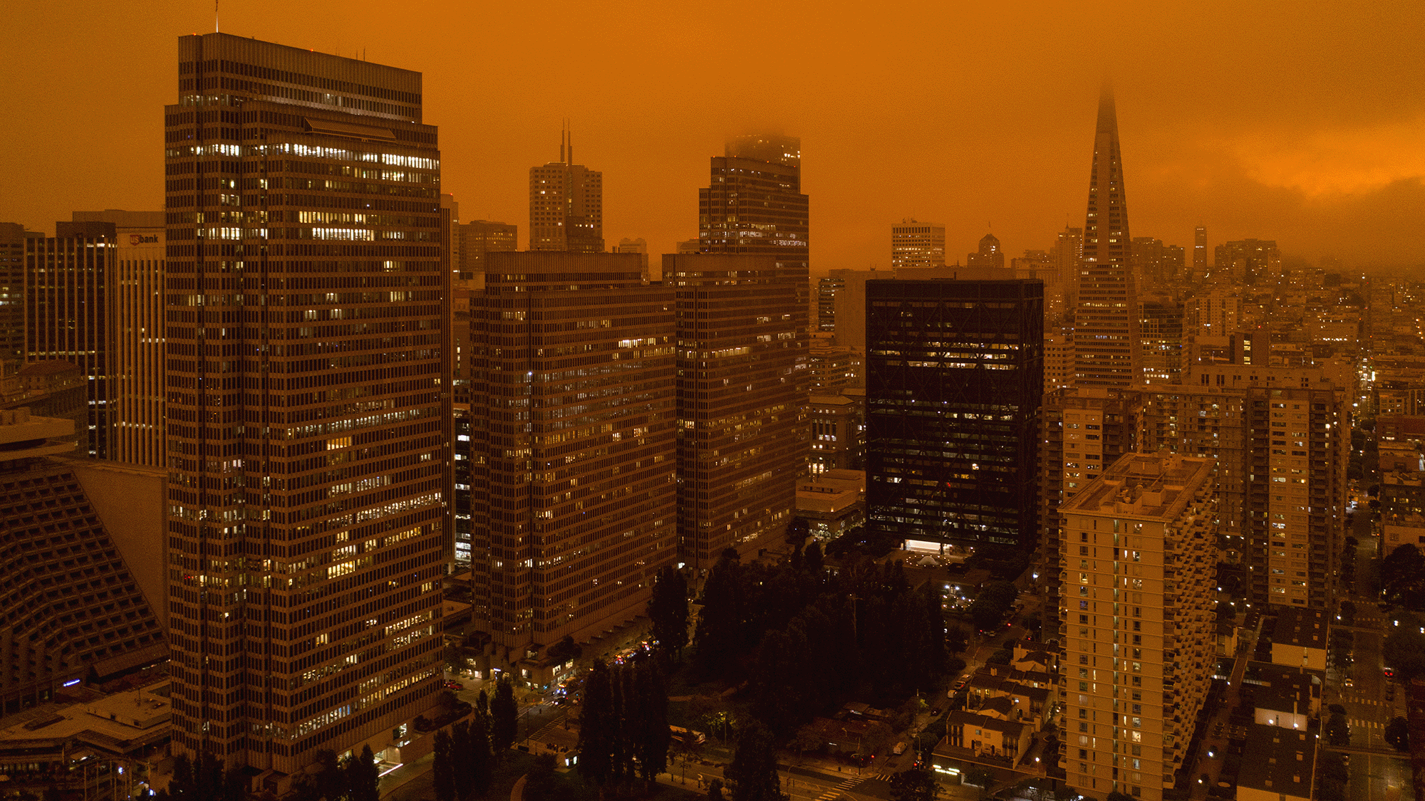 An orange haze is seen over skyscrapers in a city skyline.