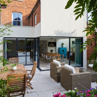 house exterior with red brick and white wall house extension wooden dinning table and chair and brown sofa