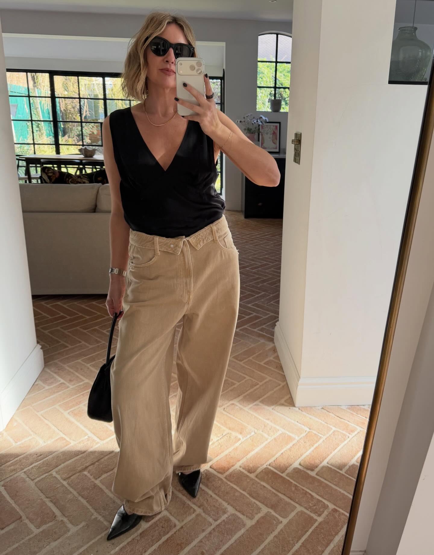 Emma Rose Thatcher wears brown jeans with a black V-neck top and pointed heels