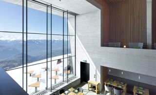 A hotel huge window to snow and mountains, inside chairs and tables