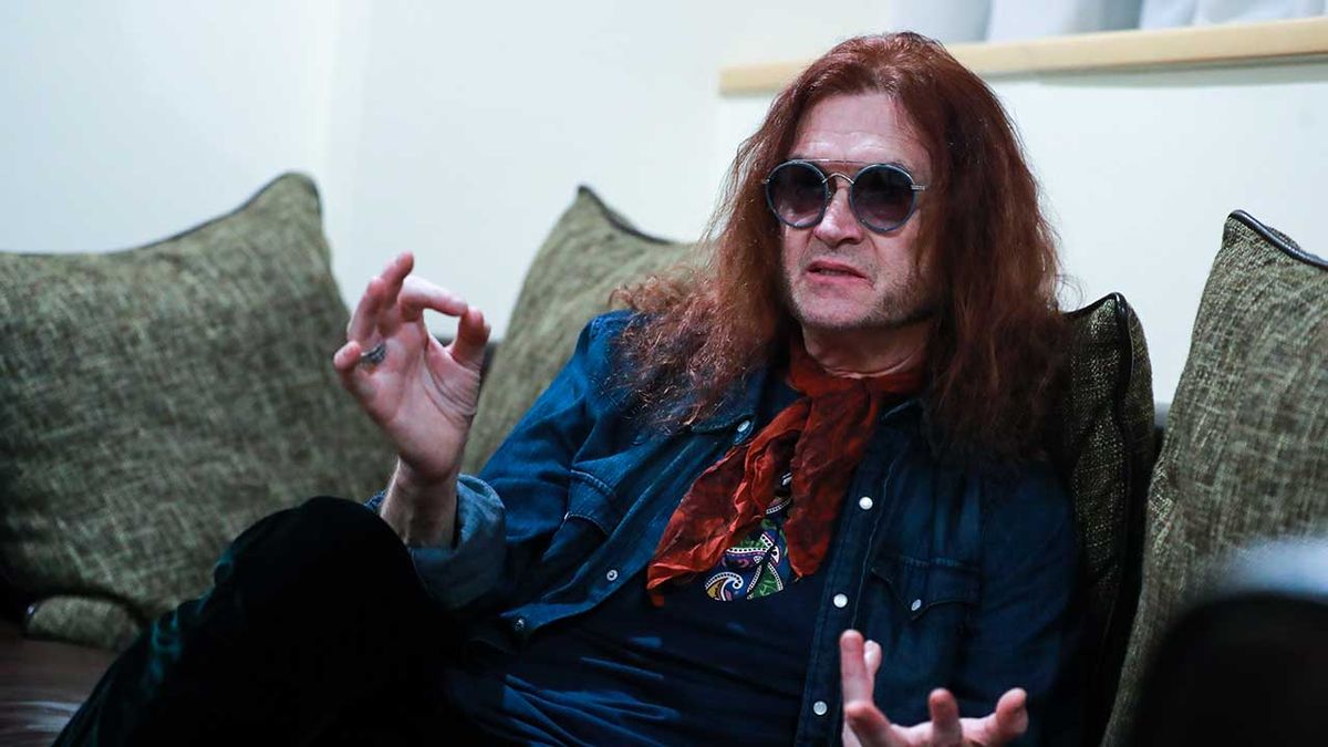 Glenn Hughes sitting on a sofa backstage 