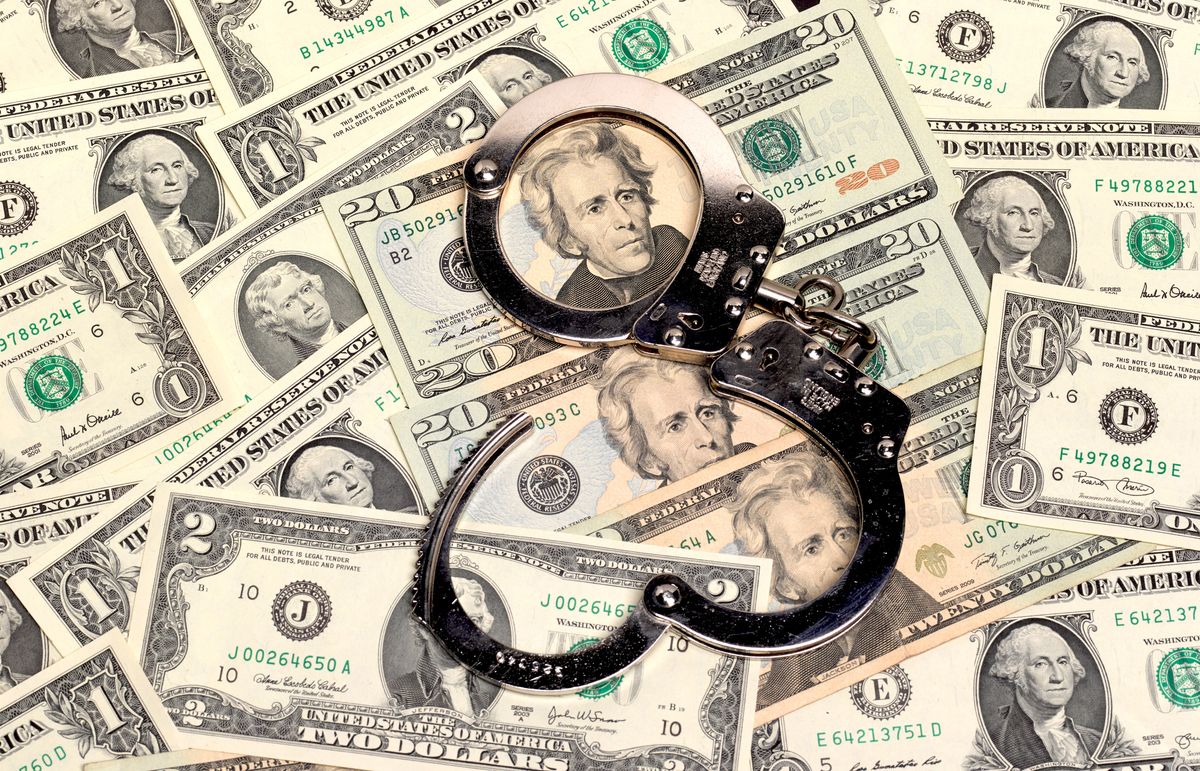 A pair of handcuffs resting on some dollars.