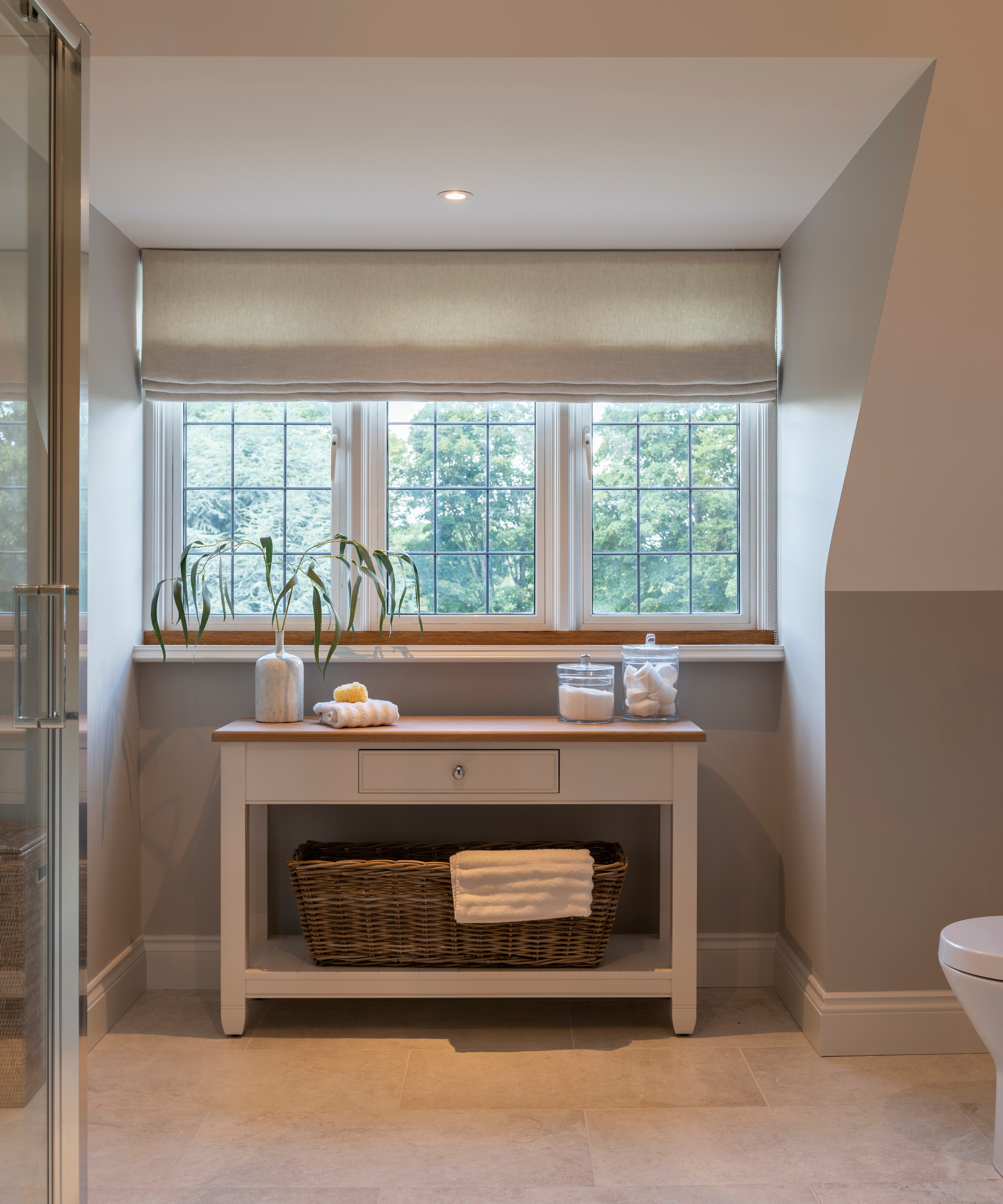 console style table in space below dormer window in bathroom