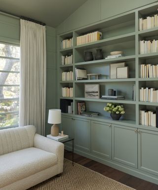 library with green bookcase, sisal rug, white sofa and white curtains