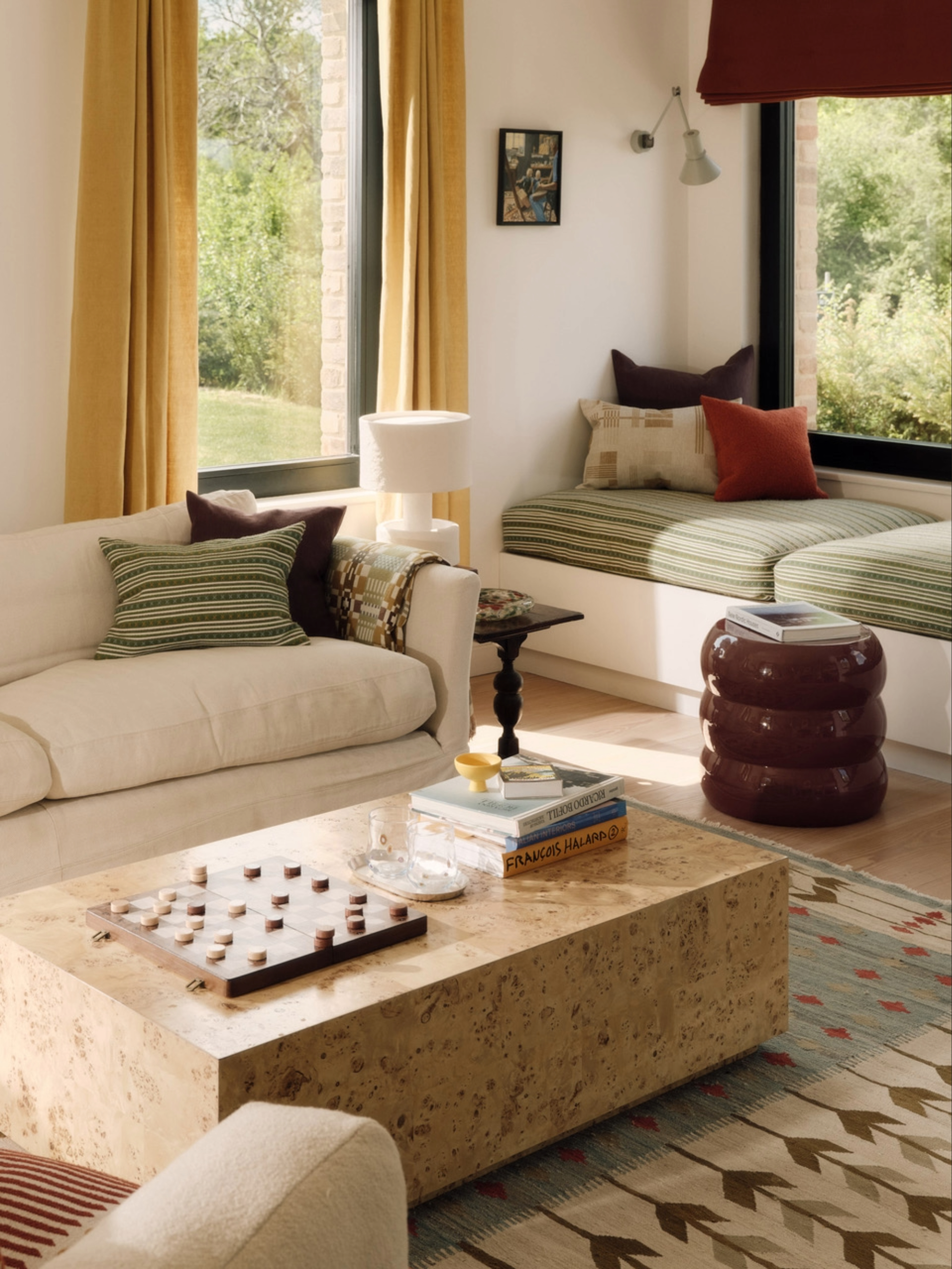 a living space with a white sofa and a burl coffee table, with a window seat behind