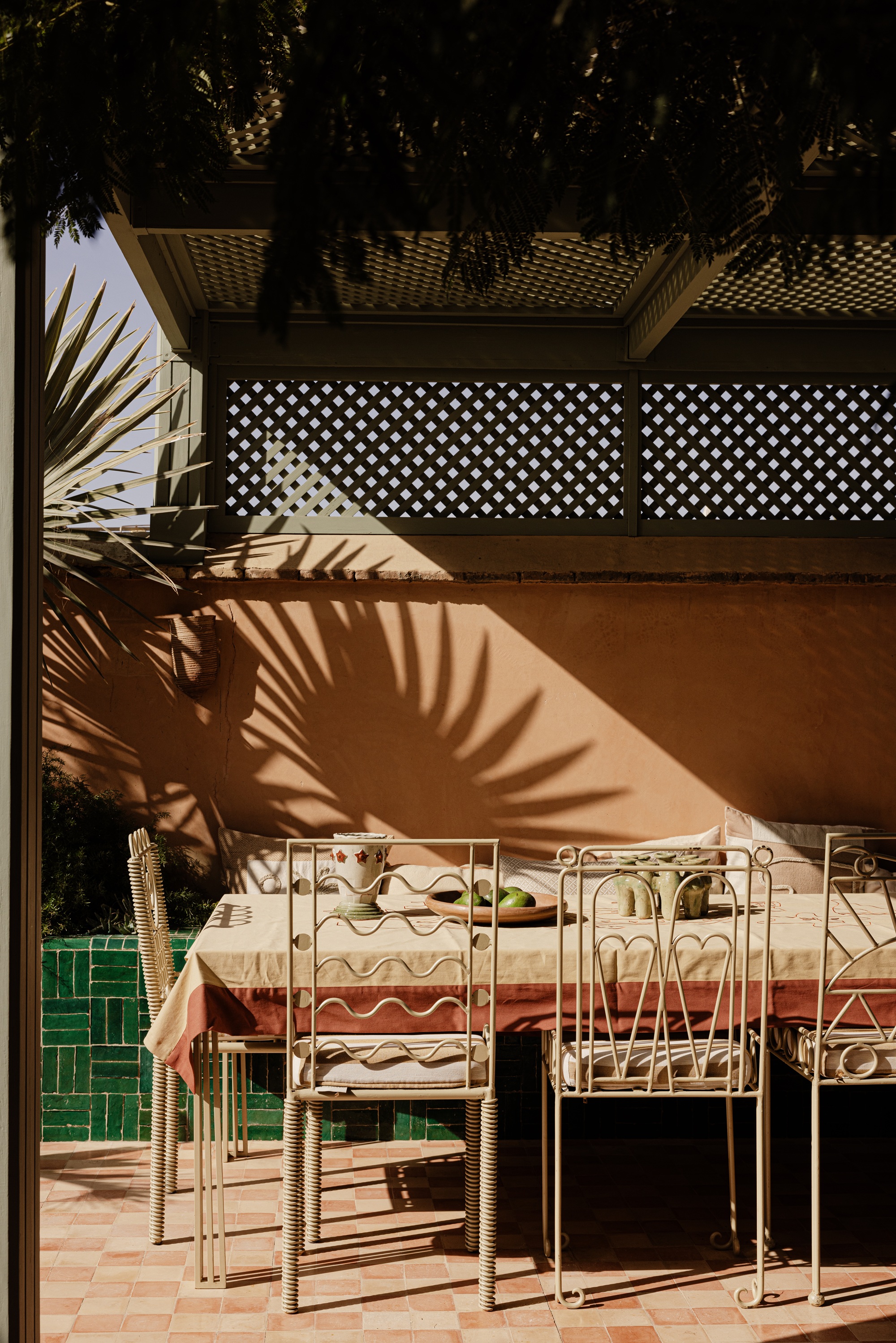 an outdoor dining space with a green tiled bench and terracotta walls