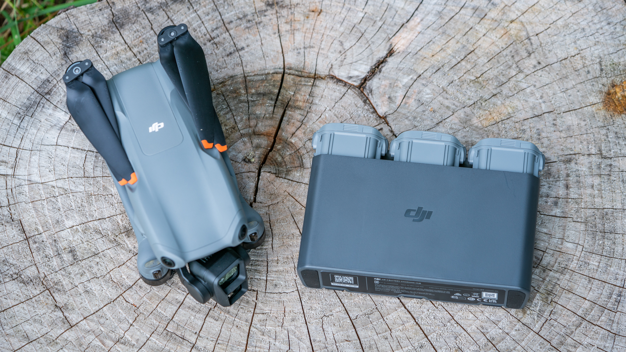 DJI Air 3 drone on a tree stump next to battery charger pack