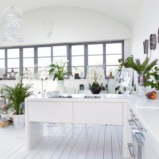 White open plan kitchen living room with painted floor boards and pendant light