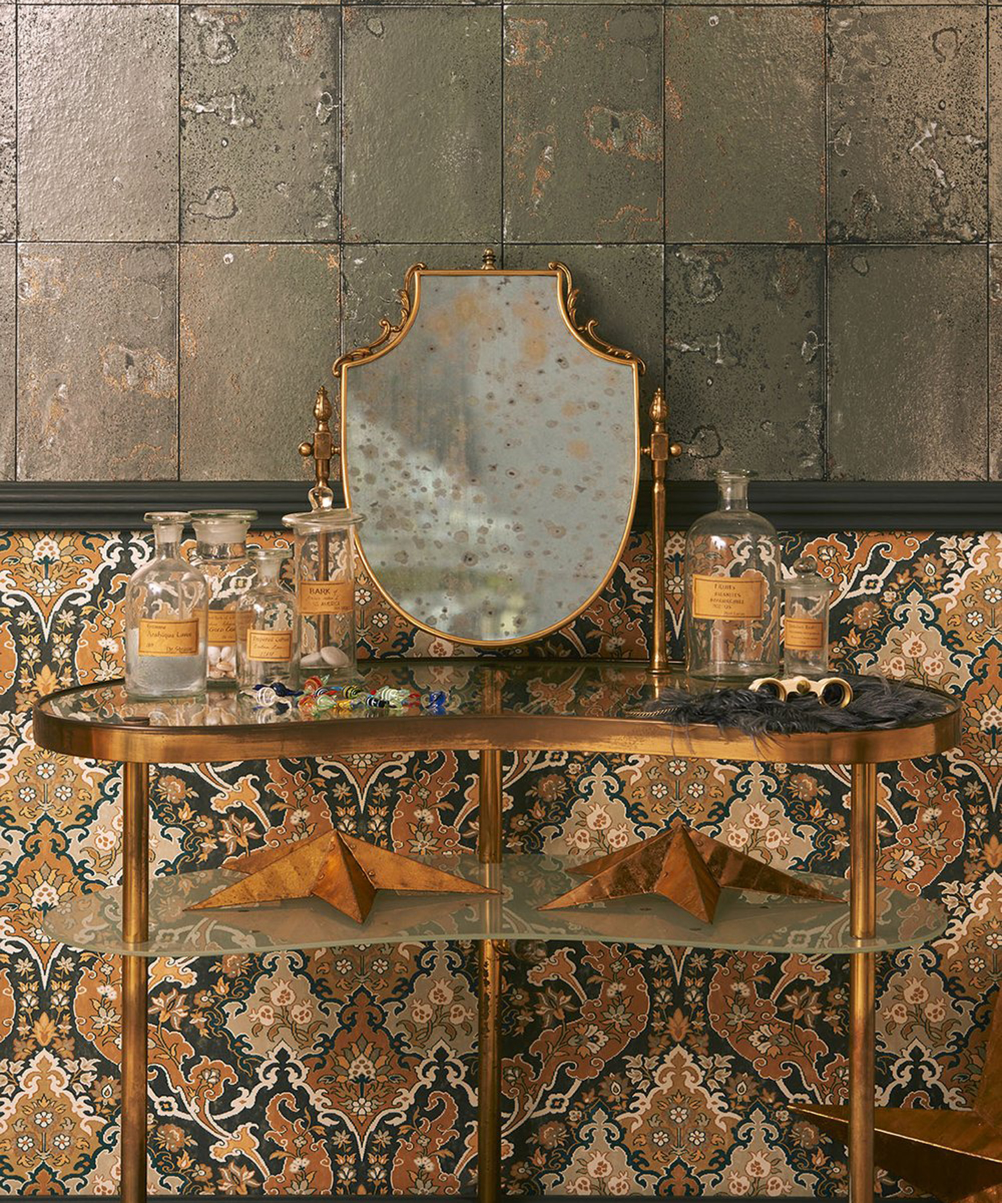 Cole and Son antique mirror effect wallpaper with a brass and glass table with apothecary bottles