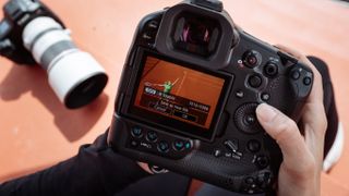 Canon EOS R1 camera held in a person's hands as they use the screen on the rear