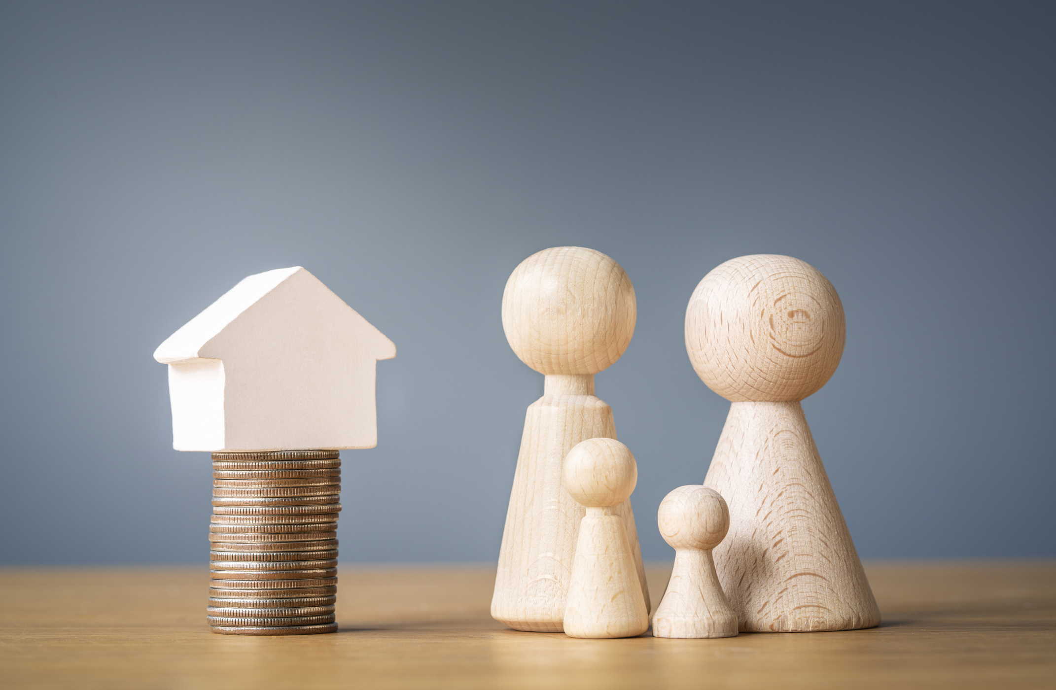 Wooden figures next to a stack of coins with a small white house on top