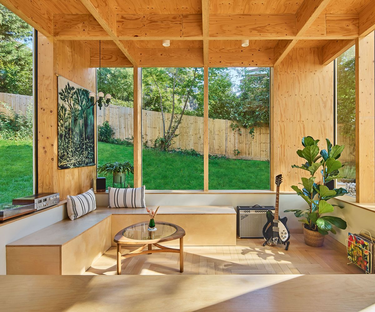 rear living room extension to a 1970s house with built-in bench seating and glazing looking over the garden