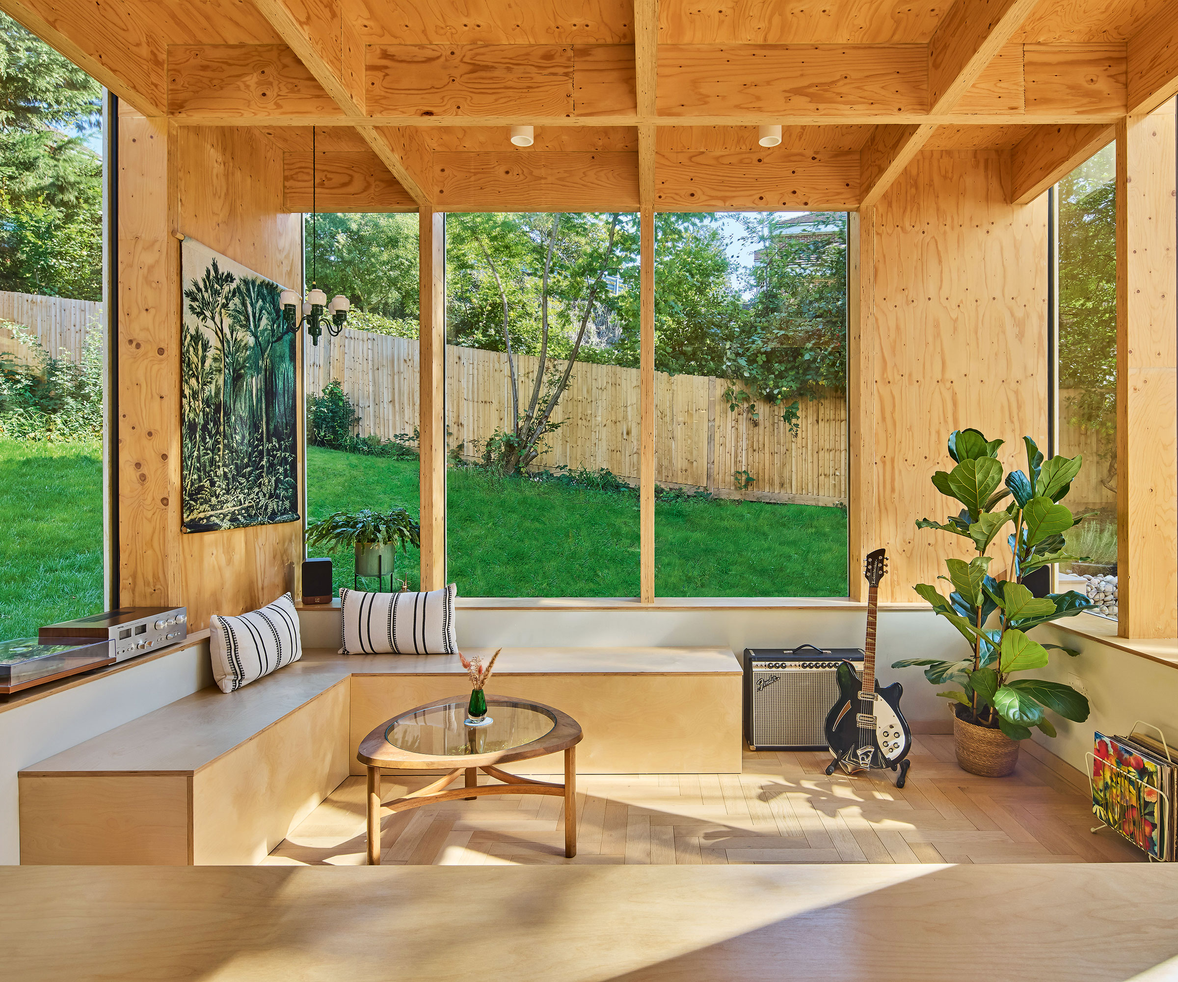 rear living room extension to a 1970s house with built-in bench seating and glazing looking over the garden