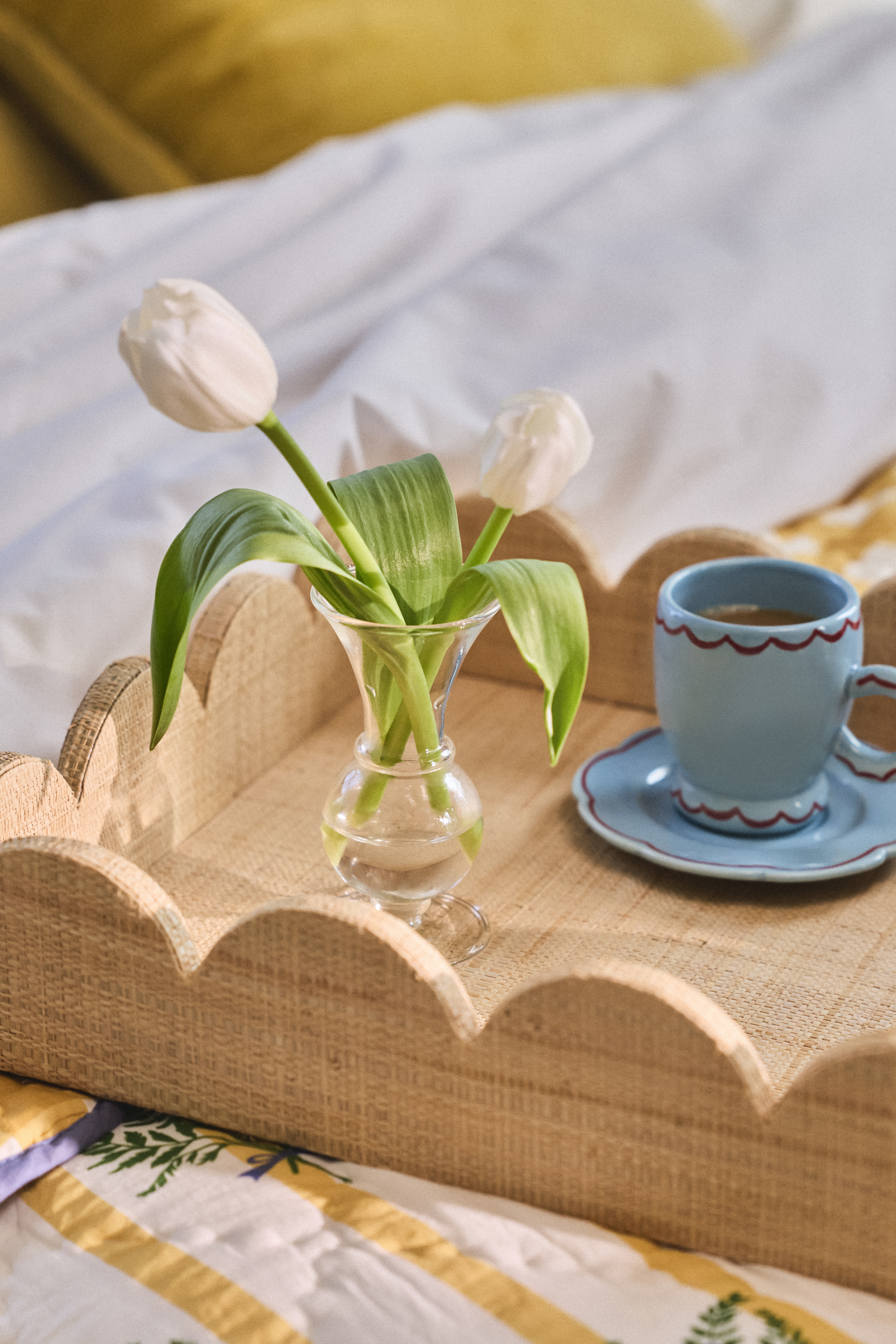 A hotel suite's interior, filled with patterned green, white, and yellow textiles, sculptural wooden and marble pieces, framed artworks in classical frames, and design-y board games.