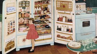 a vintage photo of a little girl getting cake from a large fridge