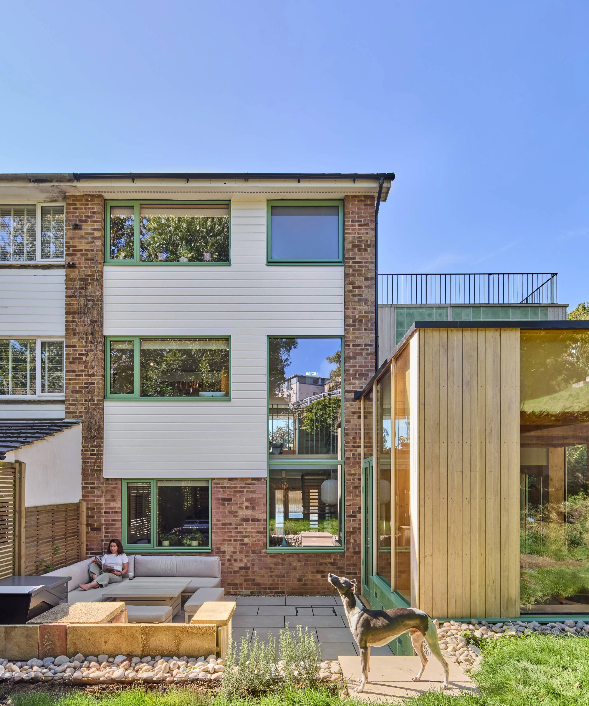 Back exterior of the house with owner and dog in the shot