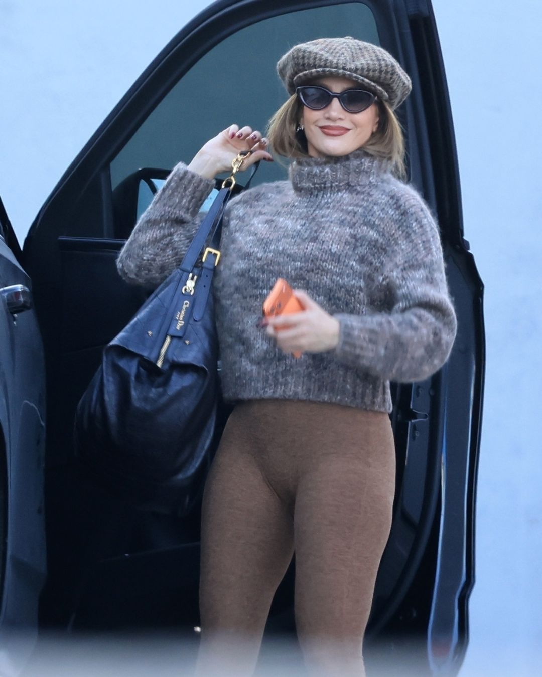 Jennifer Lopez wears a marl knit jumper with brown marl leggings and a knitted baker boy hat.