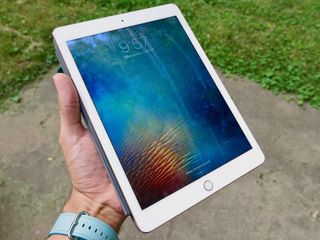 A 9.7-inch iPad Pro is shown held in someone's hand.