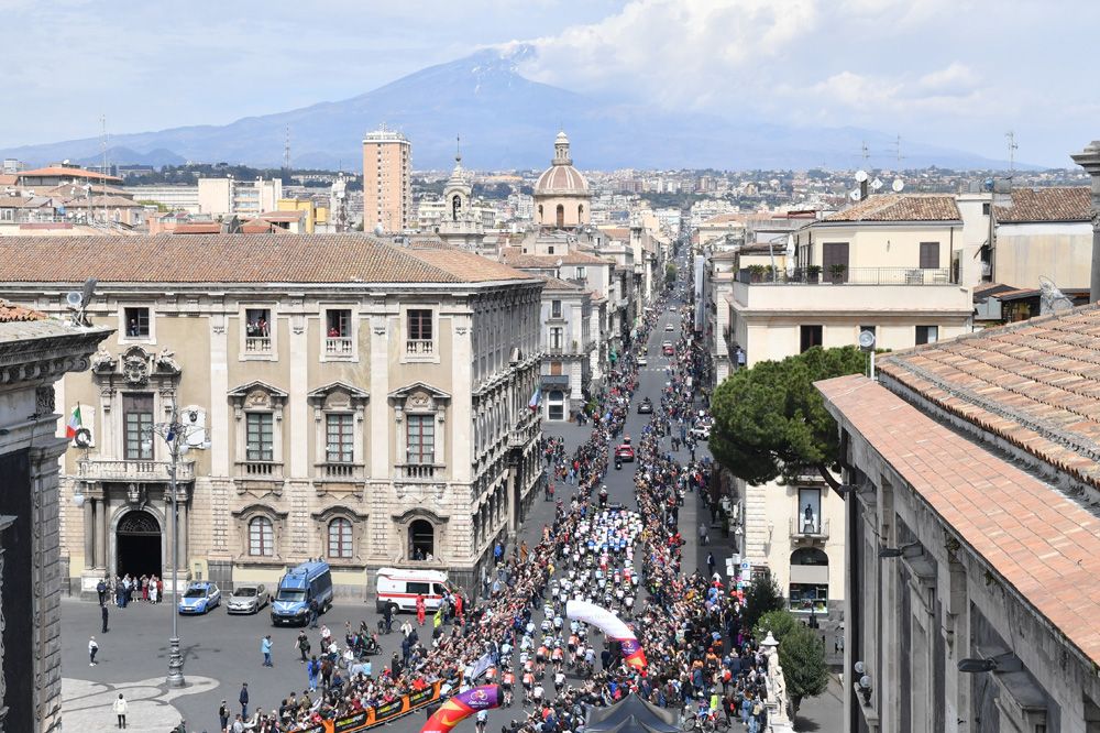 Mount Etna smokes in the background as the riders leave out of Catania