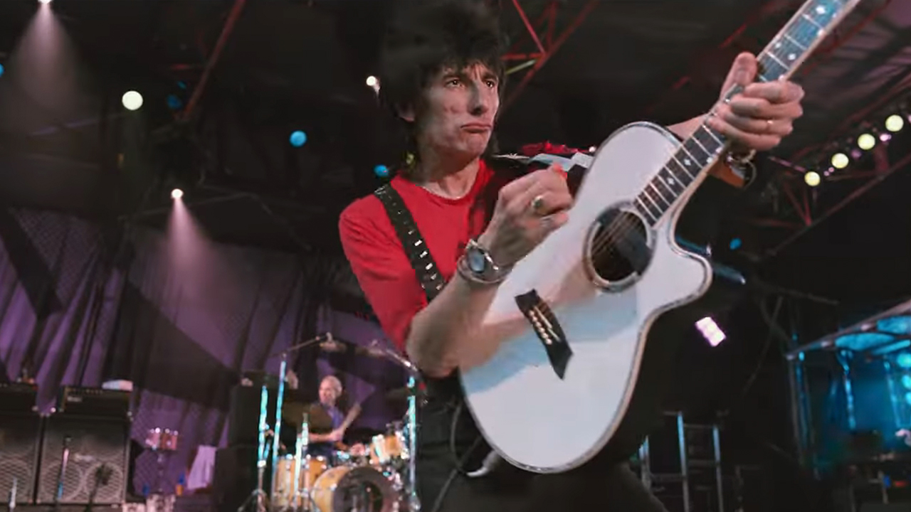 ステージで白いギターを弾くロン・ウッド